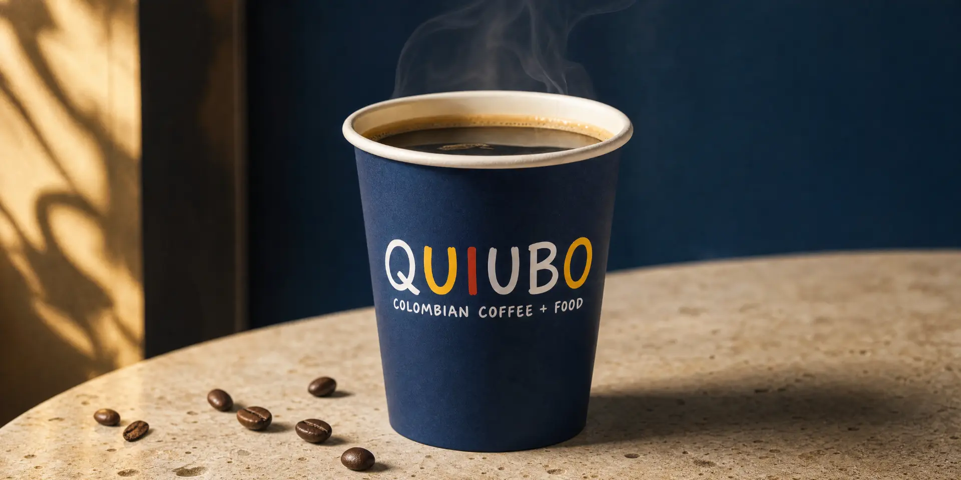 Americano QUIUBO humeante en vaso de papel azul con granos de café sobre una mesa de piedra