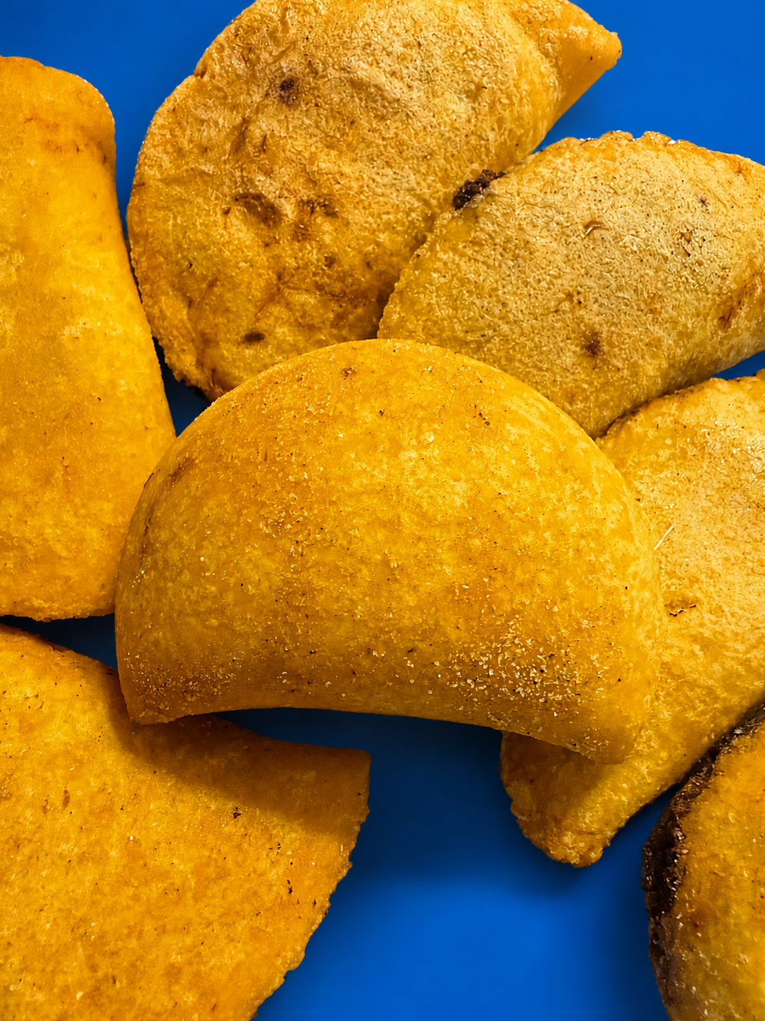 Empanadas colombianas doradas recién fritas sobre fondo azul
