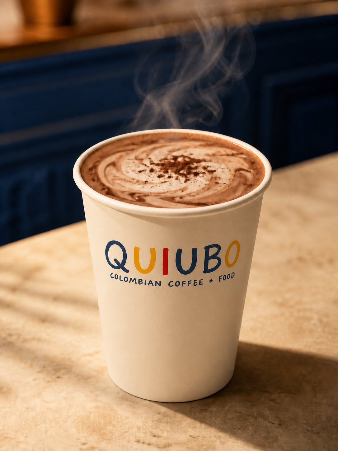 Mocha caliente QUIUBO humeante en vaso de papel crema con remolino de cacao
